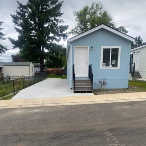 A blue mobile home in a residential neighborhood during the arrival of all 17 homes to Clairmont.