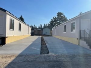 Two mobile homes in the middle of a driveway captured in photos.