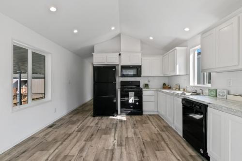 A white kitchen with wood floors and black appliances.