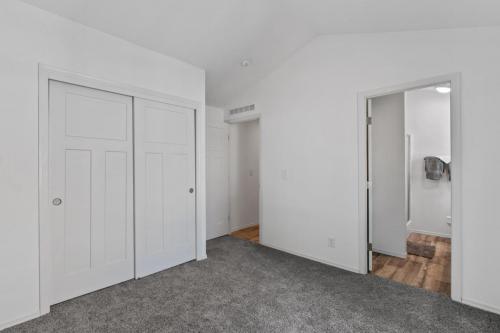 An empty room with white closets and gray carpet.