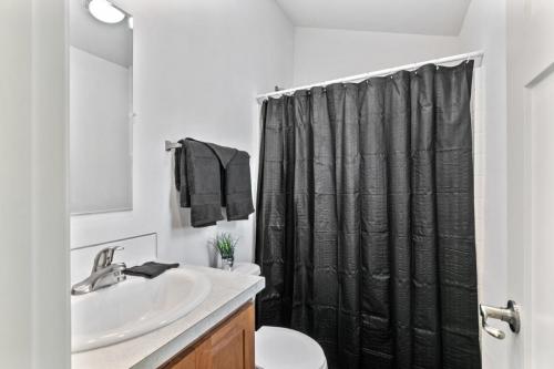 A bathroom with a black shower curtain and toilet.