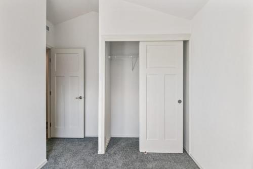 An empty room with white closet doors and gray carpet.