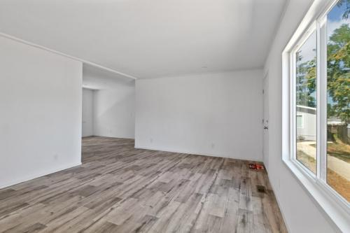 Empty living room with white walls and hardwood floors.