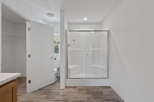 A white bathroom with wood floors and a shower stall.