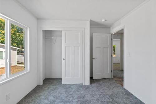 An empty room with white closets and a window.