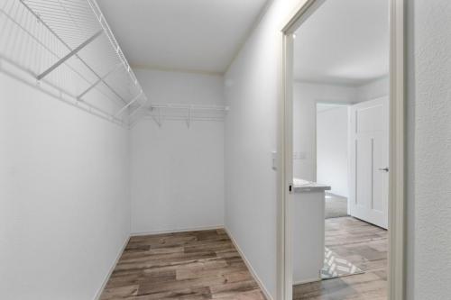 A hallway with a white closet and wooden floor.