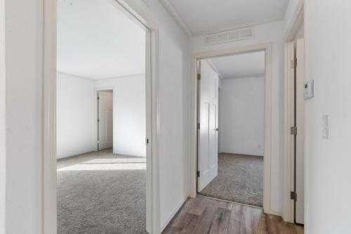 An empty hallway with white walls and hardwood floors.