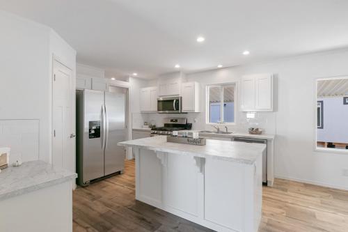A white kitchen with hardwood floors and stainless steel appliances.