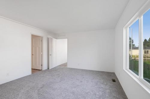 An empty room with white walls and gray carpet.