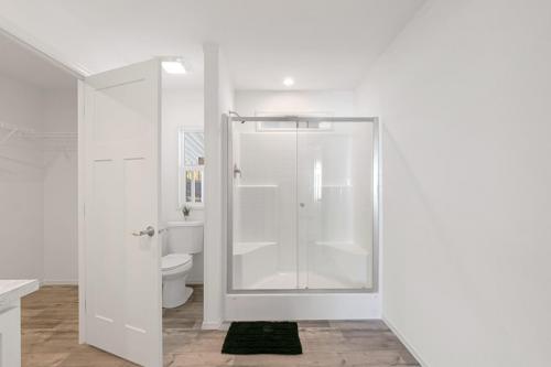 A white bathroom with wood floors and a shower stall.