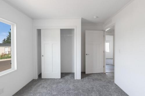 An empty room with two closets and a window.