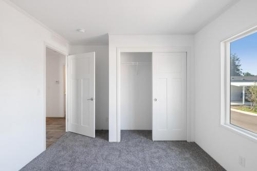 An empty room with white doors and gray carpet.