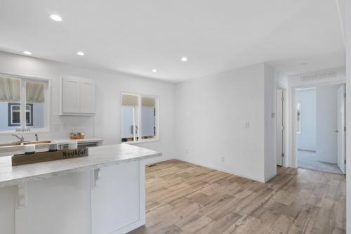 An empty kitchen with white cabinets and hardwood floors.