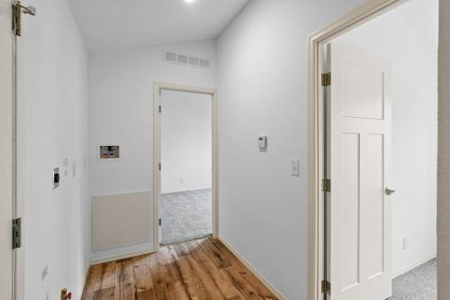 A hallway with white walls and hardwood floors.