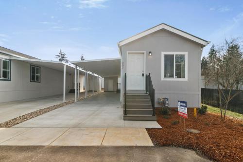 A gray mobile home with a driveway in front of it.