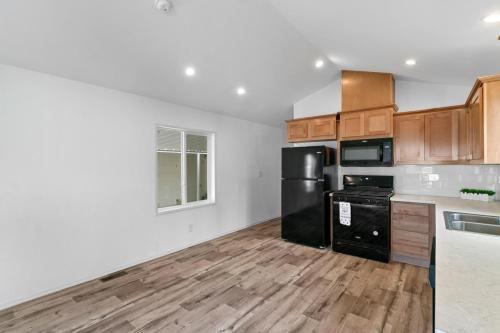 An empty kitchen with wood floors and black appliances.